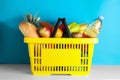 Shopping basket with grocery products on white table