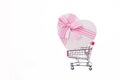 shopping basket with a large heart-shaped gift and a pink bow on a white background