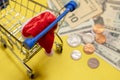 Shopping basket, santa hat, dollars and cents on a yellow background. Selective focus. The concept of Christmas discounts, New
