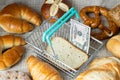 Shopping basket with US dollars and a slice of dry bread, around various types of bread and pastries, The concept of rising food