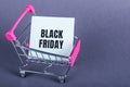 Shopping cart and black friday text on paper tear. Gray background with copy space