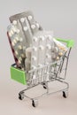 Shopping cart with blisters of tablets and pills concept of self-treatment and purchase of medicines