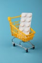 Shopping cart on a blue background with a medicine plate white pills inside