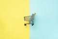 Shopping cart on blue and yellow background. Minimalism style. Creative design. Top view with copy space. Shop trolley Royalty Free Stock Photo
