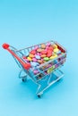 Shopping cart for children\'s birthday with many colorful smarties sweets in different colors and blue background Royalty Free Stock Photo