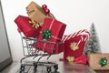 Shopping cart with christmas gifts on laptop computer. Online shopping, e-commerce and worldwide shipping concept Royalty Free Stock Photo