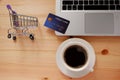 Shopping cart and credit card and laptop computer with black coffee in white cup. Concepts of online shopping or delivery where Royalty Free Stock Photo