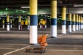 The shopping cart is empty in the Parking lot. Empty underground Parking of a supermarket. Blurred green lights of empty Royalty Free Stock Photo