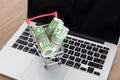 A shopping cart with euro banknotes on a computer keyboard