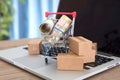 A shopping cart and express parcel full of Canadian dollar bills on a laptop keyboard