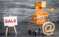 A shopping cart filled with cardboard boxes and an easel with the word Sale and email symbol. Advertising sale, marketing Royalty Free Stock Photo