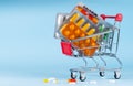 Shopping cart filled with pills. Blue background. Concept: full set of medicines in the store Royalty Free Stock Photo