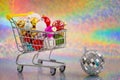 shopping cart full of colorful xmas baubles on blurred rainbow color background Royalty Free Stock Photo