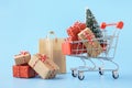 Shopping cart full of various gift boxes and a Christmas tree Royalty Free Stock Photo