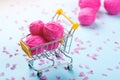 Shopping cart full of wool knitting balls. Knitting background. Pink wool yarns. Colorful pink threads on blue paper background. Royalty Free Stock Photo