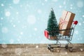 Shopping cart with gift or present and fir tree on snowy effect background. Christmas and New year sale concept. Greeting card. Royalty Free Stock Photo