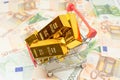 Shopping cart with gold bullion bars and euro currency notes security investment buying metaphor concept