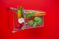 Shopping cart with groceries on a red background.grocery consumer basket.food cost.Vegetables and fruits price .food Royalty Free Stock Photo