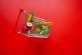 Shopping cart with groceries on a red background.grocery consumer basket.food cost.Vegetables and fruits price increase Royalty Free Stock Photo