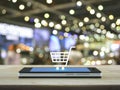 Shopping cart icon on modern smart phone screen on wooden table Royalty Free Stock Photo