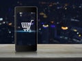 Shopping cart Icon on modern smart phone screen on wooden table Royalty Free Stock Photo