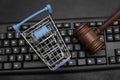 Shopping cart and judges hammer on the keyboard. Online Auction