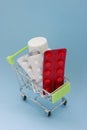 Shopping cart loaded with pills on blue background. The concept of medicine and the sale and delivery of drugs. Copy space Royalty Free Stock Photo