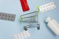 Shopping cart loaded with pills on blue background. The concept of medicine and the sale and delivery of drugs. Copy space Royalty Free Stock Photo