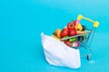 Shopping cart with medical mask with fruits and vegetables on a blue background. online shopping on quarantine concept.