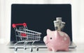 Shopping cart and piggy bank with laptop on the desk Royalty Free Stock Photo