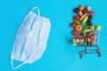 Shopping cart with medical mask with fruits and vegetables on a blue background. online shopping on quarantine concept