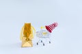 Shopping cart in a red cap with gold gift bag on a white background. The concept of winter, new year, christmas shopping