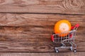 Shopping cart with rotten orange on the old wood background. Mold on food. The concept of selling spoiled food. Royalty Free Stock Photo