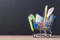 Shopping cart with school supplies over chalkboard background Royalty Free Stock Photo