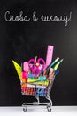 Shopping cart with school supplies over chalkboard background Royalty Free Stock Photo