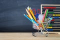 Shopping cart with school supply in front of blackboard. Back to school concept. Royalty Free Stock Photo