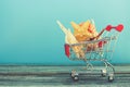 Shopping cart with seashells on blue background.