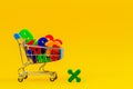 Shopping cart or supermarket trolley full of colorful numbers on yellow background Royalty Free Stock Photo