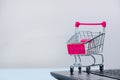 Shopping cart or supermarket trolley with laptop notebook on grey background, e-commerce and online shopping concept. Royalty Free Stock Photo
