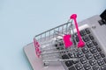 Shopping cart or supermarket trolley with laptop notebook on grey background, e-commerce and online shopping concept. Royalty Free Stock Photo