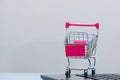 Shopping cart or supermarket trolley with laptop notebook on grey background, e-commerce and online shopping concept. Royalty Free Stock Photo