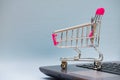 Shopping cart or supermarket trolley with laptop notebook on grey background, e-commerce and online shopping concept. Royalty Free Stock Photo