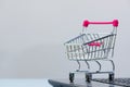 Shopping cart or supermarket trolley with laptop notebook on grey background, e-commerce and online shopping concept. Royalty Free Stock Photo