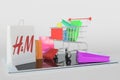 Shopping cart on a tablet computer and paper bag with H&M logo. Editorial e-commerce related 3D rendering