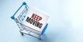 Shopping cart and tex KEEP MOVING on white paper note list. Shopping list concept on blue background Royalty Free Stock Photo