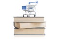 Shopping cart on top of a pile of books with reflection on white background Royalty Free Stock Photo