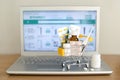 Shopping cart toy with medicaments in front of laptop screen with pharmacy web site on it. Pills, blister packs, medical bottles,