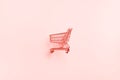 Shopping cart on trendy coral color background. Minimalism style. Shop trolley at supermarket. Sale, discount, shopaholism concept