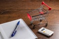 Shopping cart and trolley on table with calculator, pen and paper. Budget of poor and low income family. Rising food and grocery