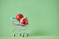 Xmas shopping, cart with two red christmas balls on a green background Royalty Free Stock Photo